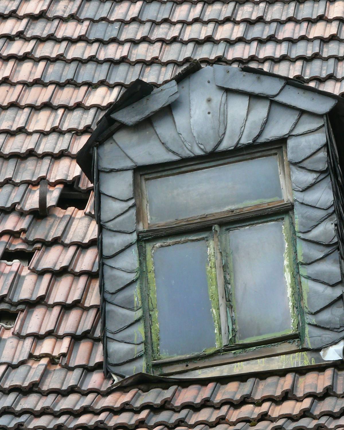 Altes Ziegeldach mit Schiefergaube, einige Ziegel fehlen