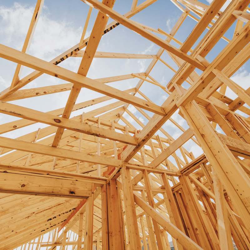 Dachstuhl aus hellem Holz vor blauem Himmel
